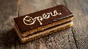 Generate an image of Opera pastry rectangular shape written opera on it plated in wooden table.webp