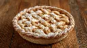 Generate an image of Apple pie basket style topped with icing sugar medium size plated in wooden table.webp
