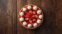 Generate an image of Strawberry open tart garnished with piping cream medium size plated in wooden table small size.webp