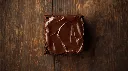 Generate an image of  double chocolate fudge brownie topped with chocolate layer in wooden table (2).webp