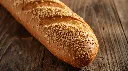 Generate an image of crusty baguette loaf topped with sesame seeds in wooden table.webp